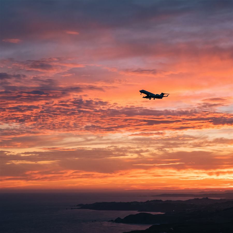 Business jet silhouette climbing into a sunset sky